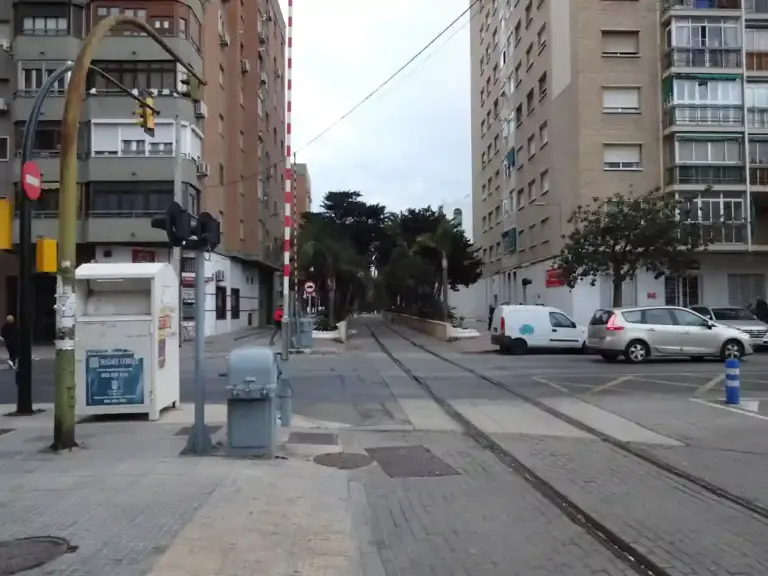 Paso a nivel urbano en Málaga con barreras, tráfico y edificios residenciales.
