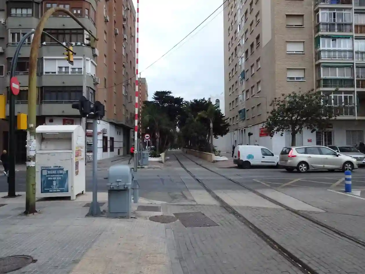 Paso a nivel urbano en Málaga con barreras, tráfico y edificios residenciales.