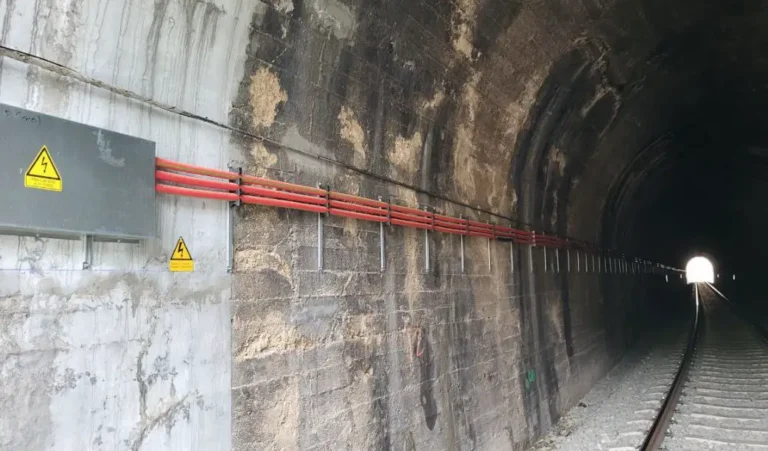 Interior de uno de los túneles de la línea Lleida-La Pobla con instalaciones eléctricas de cables rojos y vía única sobre balasto