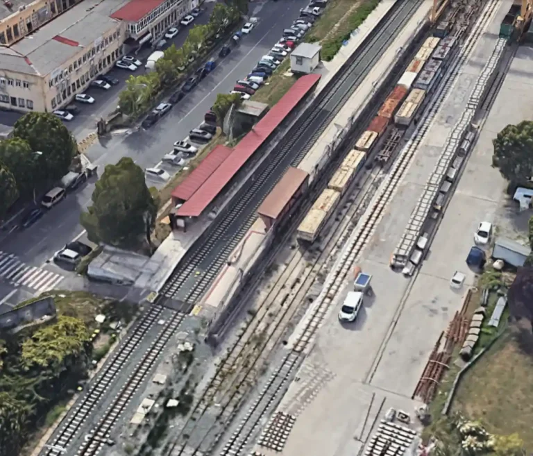 Vista aérea de la estación de viajeros de Ariz-Basauri, mostrando los andenes con marquesinas rojas, las vías de paso y una zona de carga en el lateral derecho.