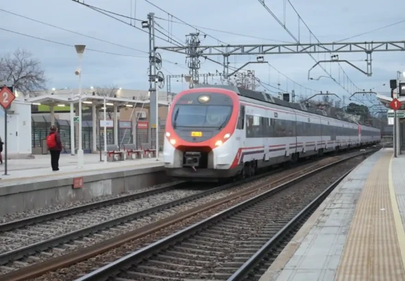 Tren de Cercanías Madrid llegando a una estación con pasajeros esperando en el andén, representando la integración del transporte ferroviario en España mediante el nuevo sistema de abono único.
