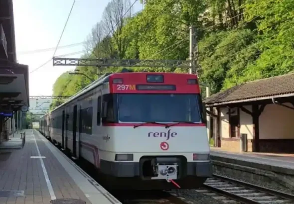 Tren de Cercanías Renfe de la serie 447 estacionado en el andén de una estación rodeada de vegetación en el País Vasco.