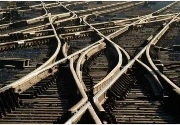Vista superior de un complejo entramado de vías de tren con múltiples desvíos, agujas y cruces de rieles sobre traviesas de madera.