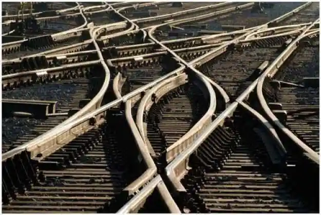 Vista superior de un complejo entramado de vías de tren con múltiples desvíos, agujas y cruces de rieles sobre traviesas de madera.