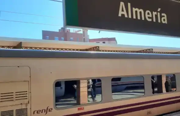 Vagón de un tren Talgo de Renfe estacionado en la estación de tren de Almería, debajo del cartel identificativo de la estación.