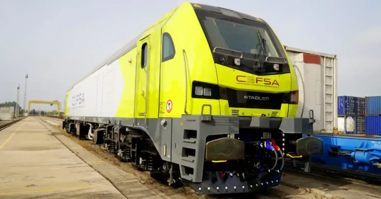 Vista frontal de una locomotora eléctrica Stadler Euro 6000 de color amarillo fluorescente y gris con el logotipo de CEFSA en una vía de carga.