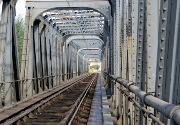 Perspectiva interior de un puente metálico con estructura de vigas grises y vía de tren única en la línea 400 en Alcolea. Se remodelará por las obras de adaptación de la autopista ferroviaria.
