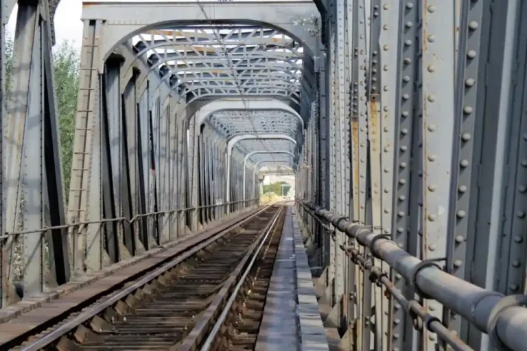 Perspectiva interior de un puente metálico con estructura de vigas grises y vía de tren única en la línea 400 en Alcolea. Se remodelará por las obras de adaptación de la autopista ferroviaria.