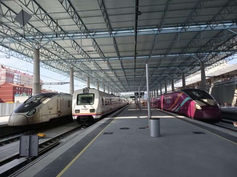 Tres trenes de Renfe, incluidos un AVE y un Avlo, estacionados bajo la gran marquesina metálica y acristalada de la renovada estación intermodal de A Coruña.