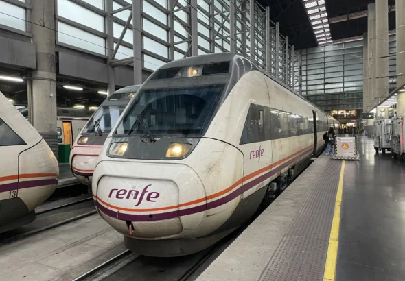 Tren Avant de Renfe de alta velocidad estacionado junto al andén de una estación ferroviaria cubierta, con la luz frontal encendida y el logotipo de la compañía visible en el frontal.