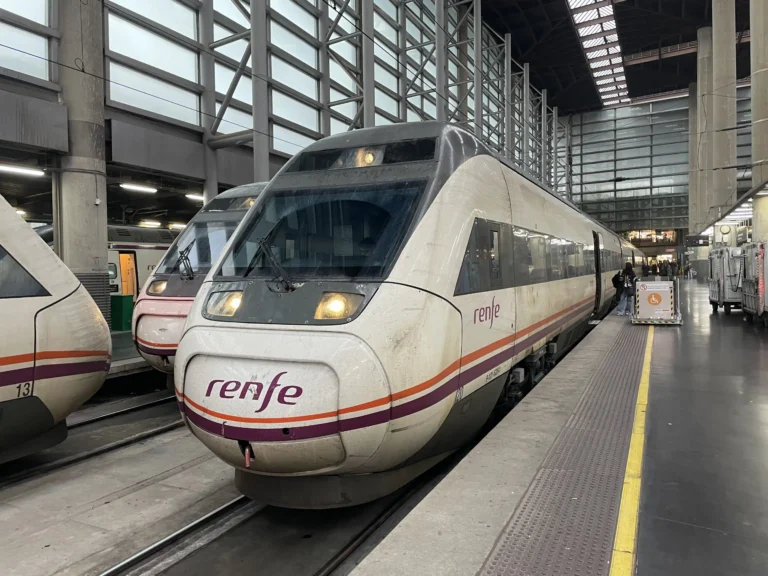 Tren Avant de Renfe de alta velocidad estacionado junto al andén de una estación ferroviaria cubierta, con la luz frontal encendida y el logotipo de la compañía visible en el frontal.