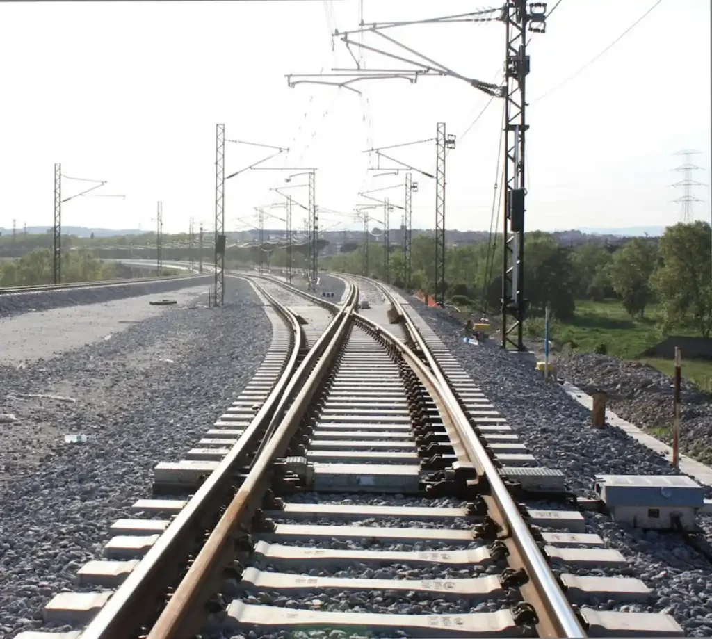 Tramo de vía ferroviaria con sistema de tres carriles para ancho mixto e infraestructura de catenaria al aire libre en Mollet.