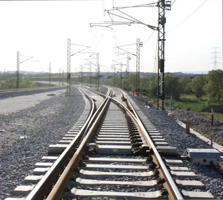 Tramo de vía ferroviaria con sistema de tres carriles para ancho mixto e infraestructura de catenaria al aire libre en Mollet.