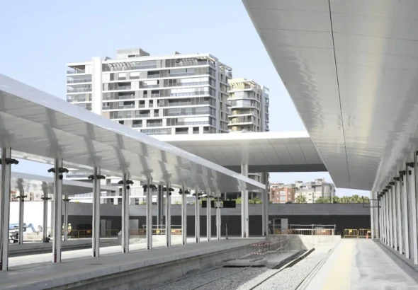 Vista de los andenes y cubiertas metálicas en construcción de la nueva estación intermodal de Almería, con las vías ferroviarias al descubierto y modernos edificios residenciales al fondo.