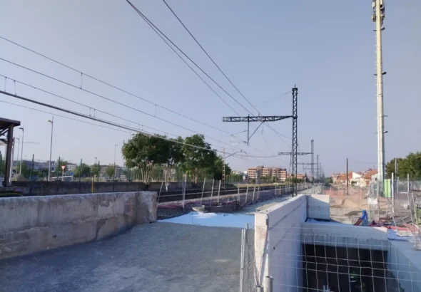 Vista panorámica de una zona de obras en el trazado ferroviario, con estructuras de hormigón, catenarias, postes de electrificación y vallas de seguridad para la ampliación de la línea de alta velocidad.