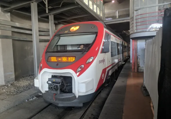 Unidad de tren Renfe Civia de la serie 465 estacionada en el andén de una estación subterránea con el indicador de destino encendido.
