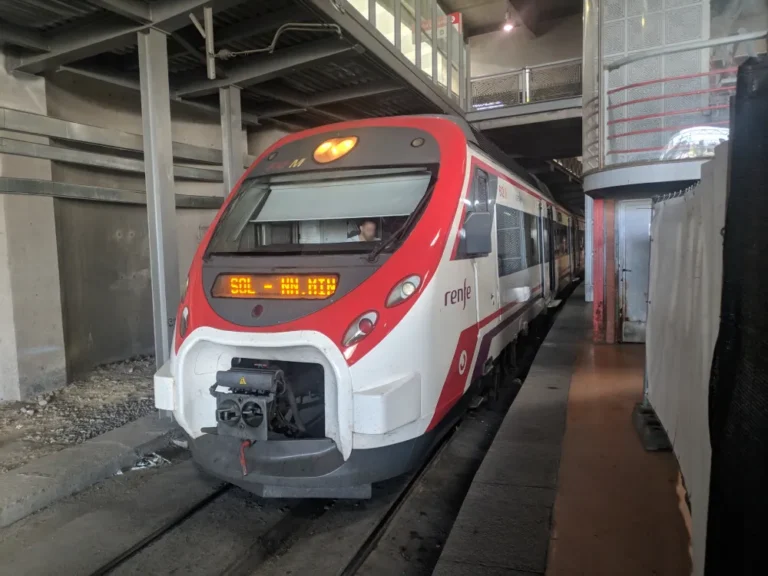 Unidad de tren Renfe Civia de la serie 465 estacionada en el andén de una estación subterránea con el indicador de destino encendido.