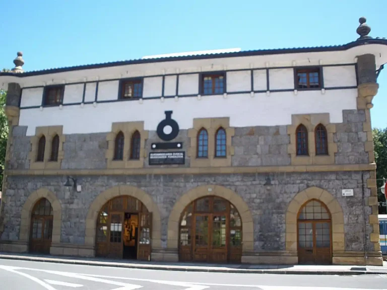 Fachada exterior del edificio histórico del Museo Vasco del Ferrocarril en Azpeitia, construido en piedra de sillería con grandes arcos en la planta baja y entramado visto en la parte superior.